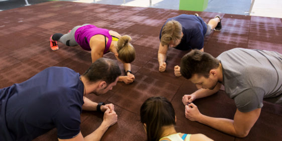 group of people exercising in gym fitness, sport, exercising, training and healthy lifestyle concept - group of people doing plank exercise in gym