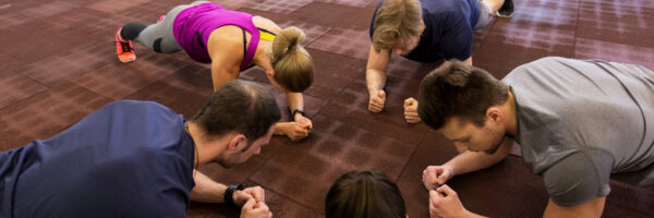 fitness, sport, exercising, training and healthy lifestyle concept - group of people doing plank exercise in gym